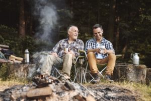 two men sitting by campfire