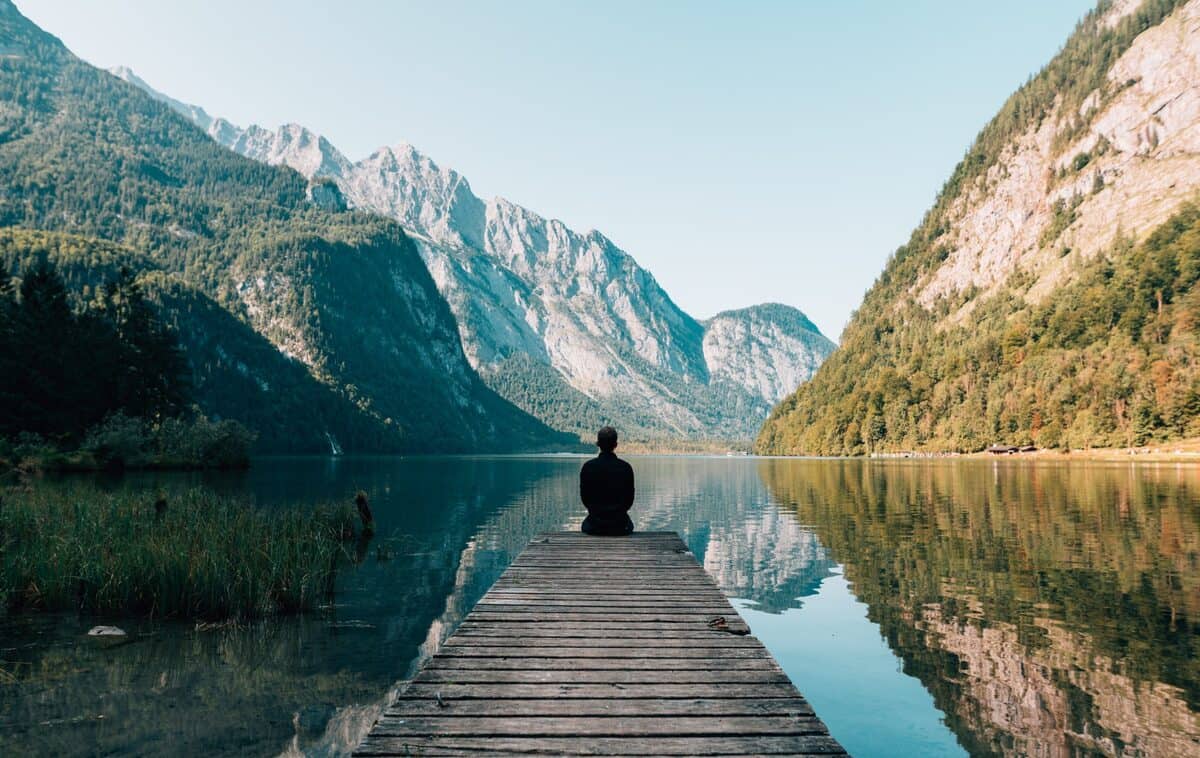 A man sitting by the water after addiction recovery and mental health support.